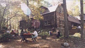 A log cabin lodge in the woods, links to about.html